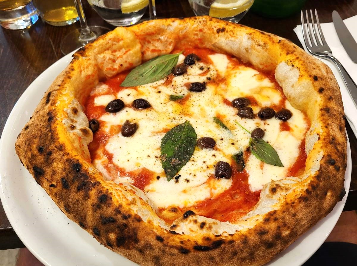 La pizza Margherita avec supplément olives servie chez Prima Volta